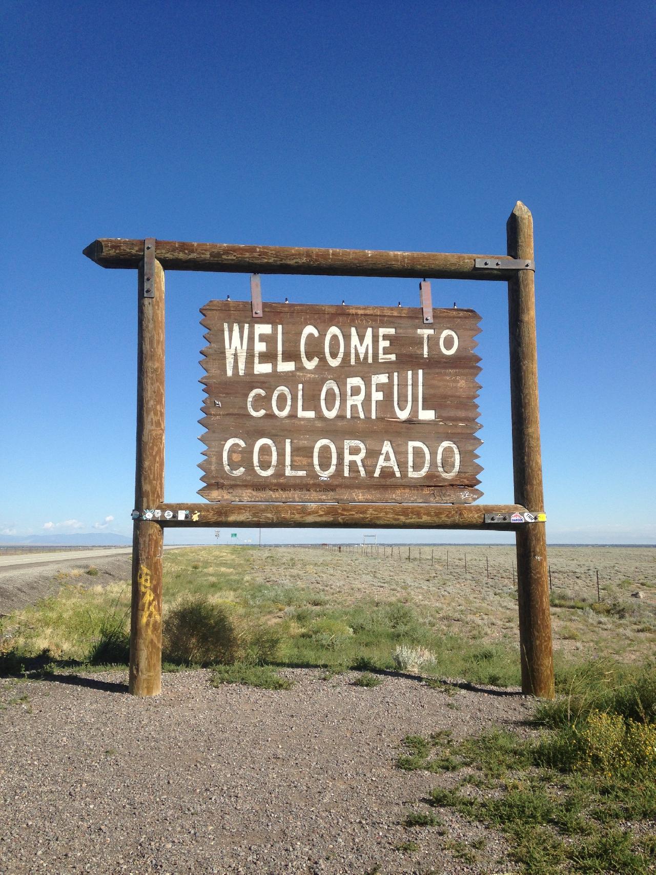 A wooden sign that says Welcome to Colorado